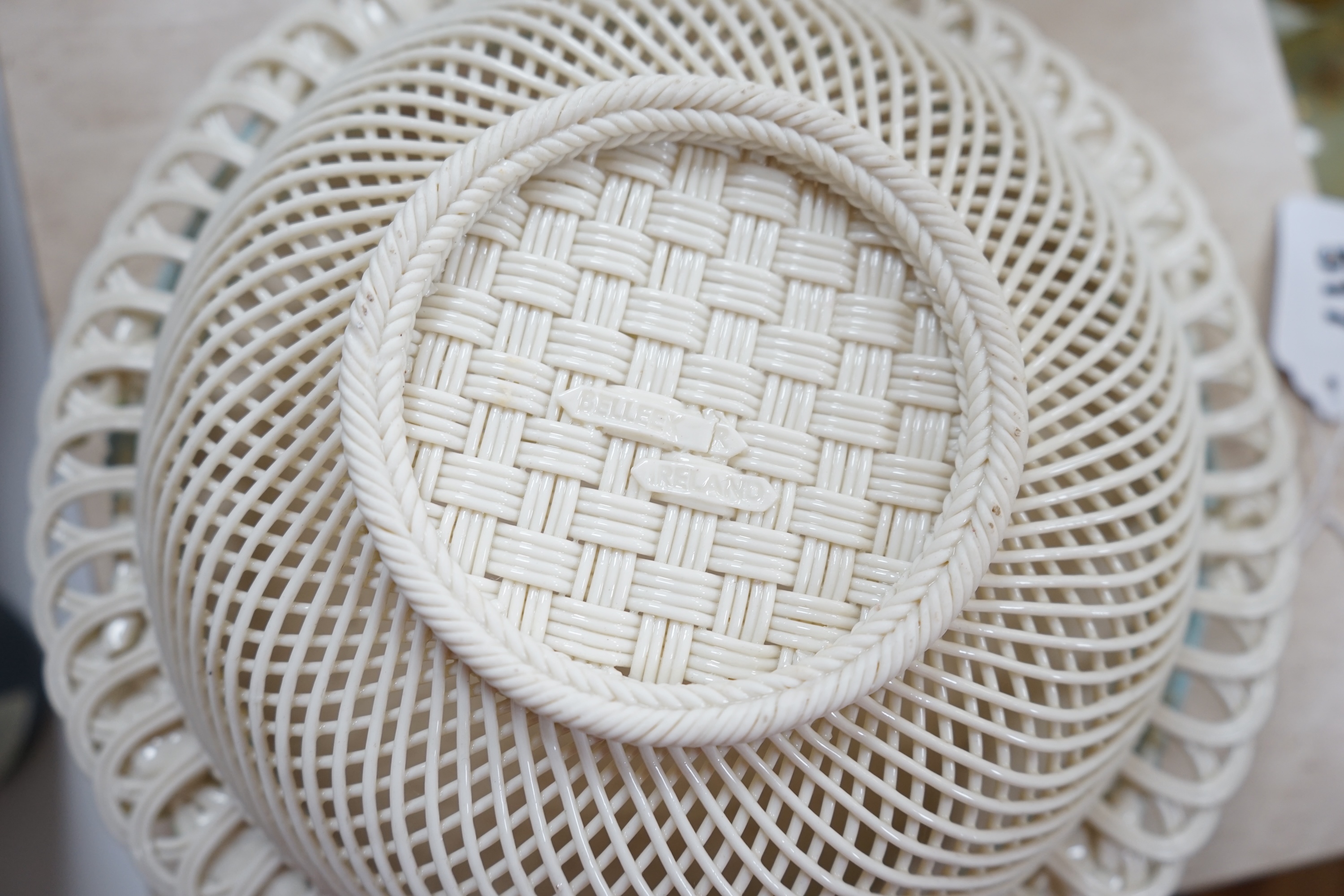 A boxed Belleek coloured basket, 28cm diameter. Condition - fair to good, some damage and wear to the box.